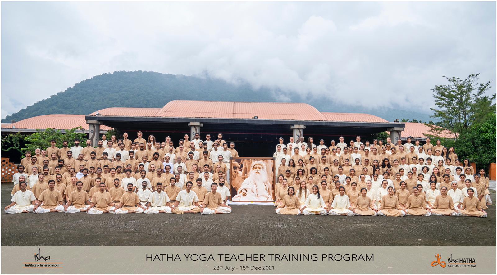 A group photograph of the 2021 Hatha Yoga Teacher Training Program at the Isha Yoga Center, with rolling green hills behind.